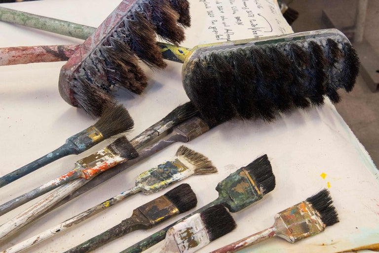 Mehrere gebrauchte Pinsel in verschiedenen Größen und Formen liegen auf einer Oberfläche.