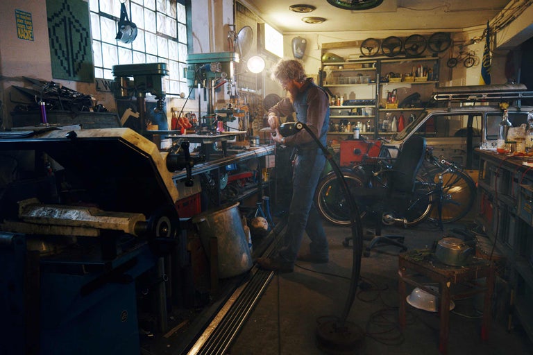 Werkstatt mit Werkzeugen, Werkbänken und einem Mechaniker bei der Arbeit