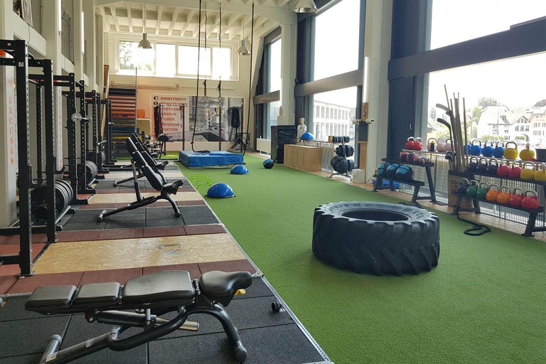 Helles Fitnessstudio mit Gewichten, Trainingsgeräten und großem Reifen