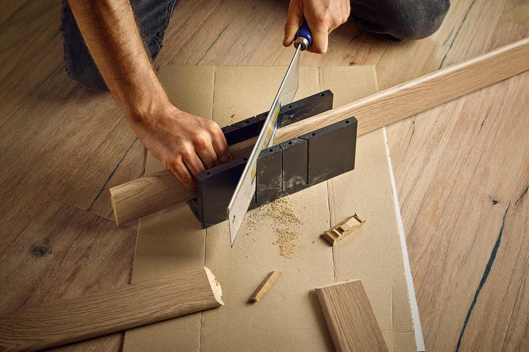 Zuschnitt von Holzleisten mit einer Säge und Schneidlade