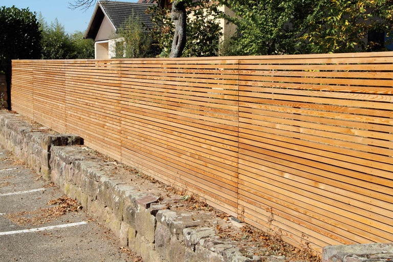 Holzzaun mit horizontalen Lamellen und Steinmauer