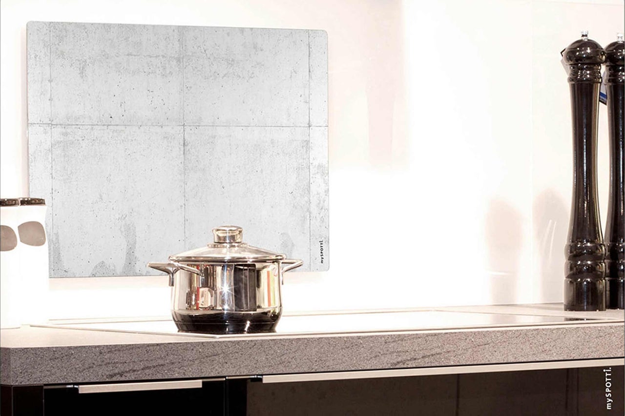 Küchenszene mit Spritzschutz im Beton-Look, Kochtopf und Gewürzmühlen