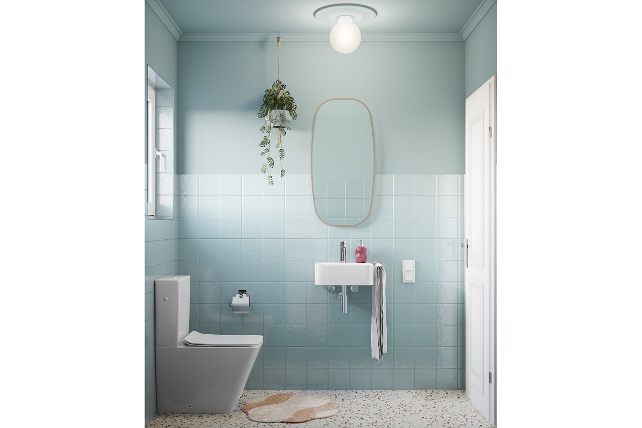 Modernes Gäste-WC mit hellblauen Wandfliesen, Terrazzo-Boden, weißem Waschbecken, Stand-WC und einem großen ovalen Spiegel.