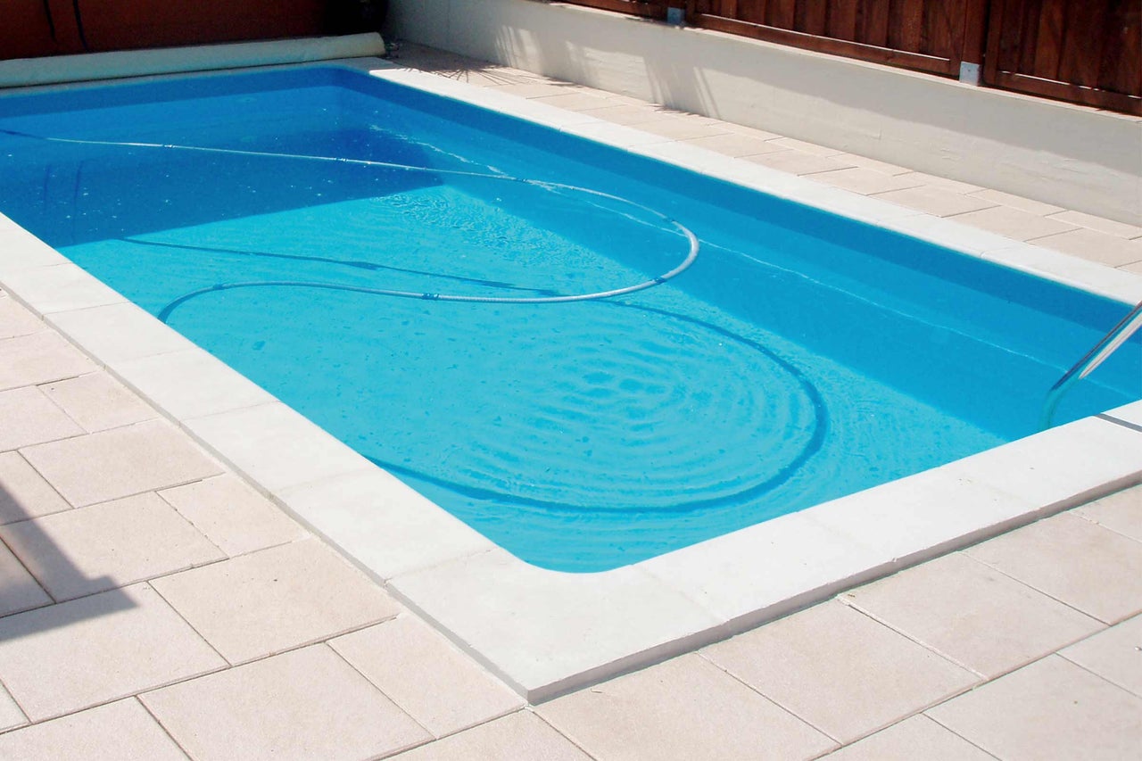 Rechteckiger Swimmingpool mit Poolreinigungsschlauch im Außenbereich