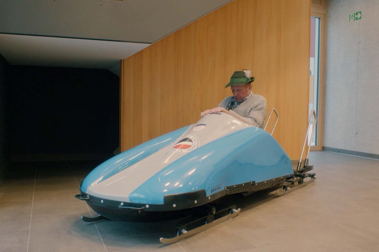 Mann sitzt in einem blauen und weißen Rennrodel im Innenraum