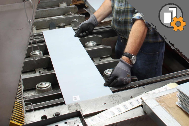 Ein Arbeiter positioniert eine Metallplatte in einer Maschine.