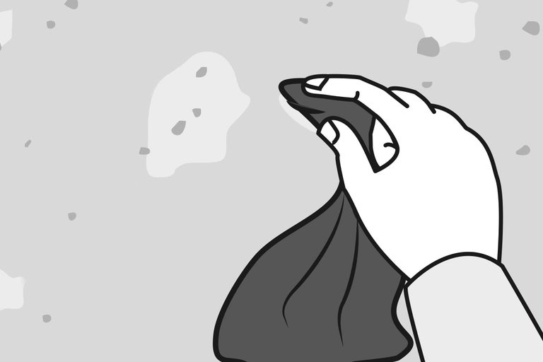 Eine Hand wischt mit einem Tuch über eine unebene Oberfläche.