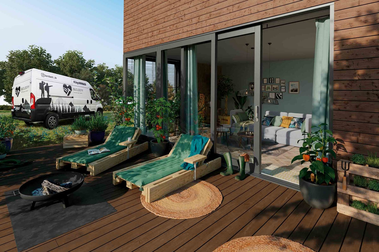 Terrasse mit Holzliegen, Feuerstelle und Blick durch eine Schiebetür ins Wohnzimmer