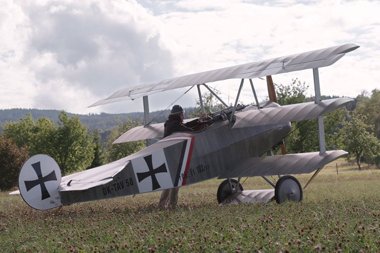 Doppeldecker Flugzeug mit Pilot auf einem Feld