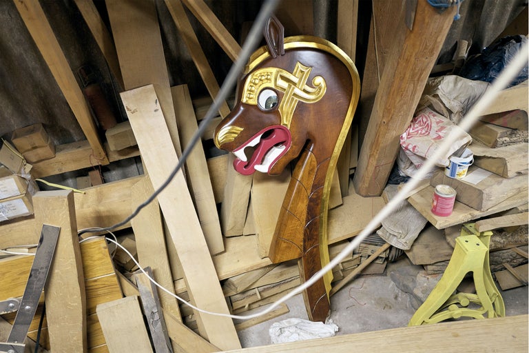 Verzierte hölzerne Bugfigur eines Schiffes zwischen Holzbrettern