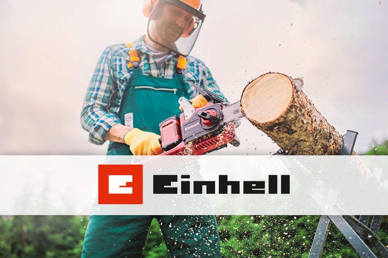 Ein Mann sägt mit einer Einhell Kettensäge einen Baumstamm, umgeben von Sägespänen. Einhell Logo.