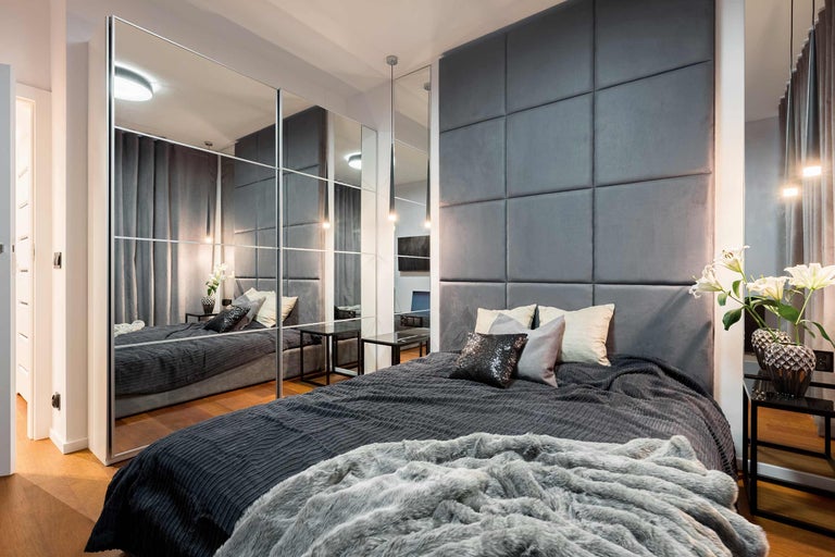 Modernes Schlafzimmer mit Bett, gepolstertem Kopfteil und Spiegelschrank