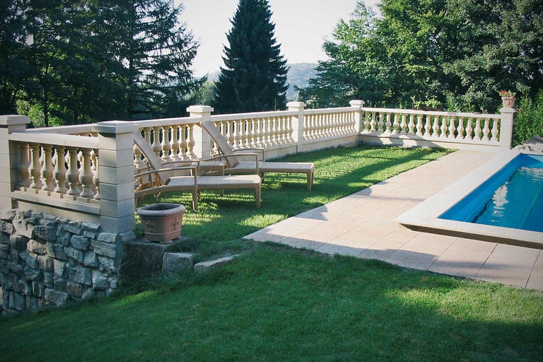 Landschaftsbild mit Pool, Liegestühlen und Balustrade