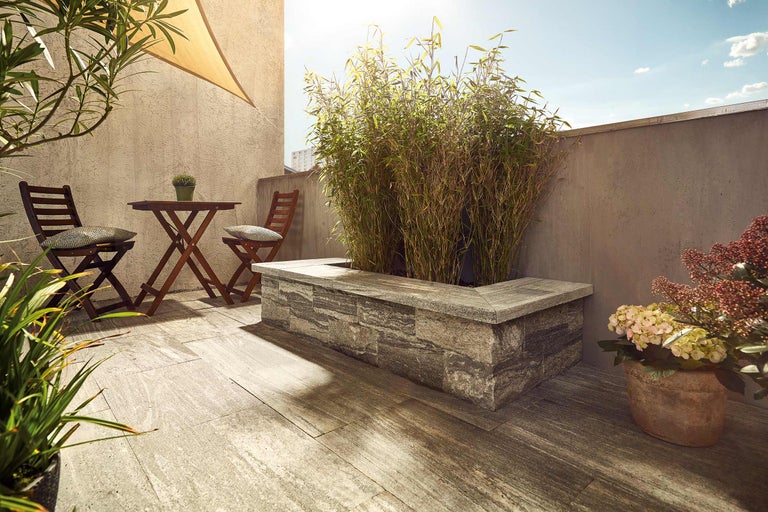 Terrasse mit Holzboden, Tisch und Stühlen sowie Pflanzkübel mit Bepflanzung