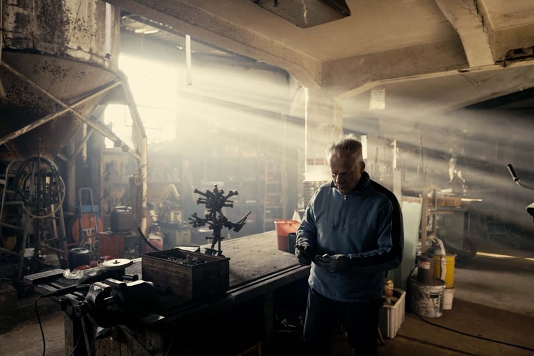 Werkstatt mit Werkbank, Werkzeug und einem Mann, der arbeitet