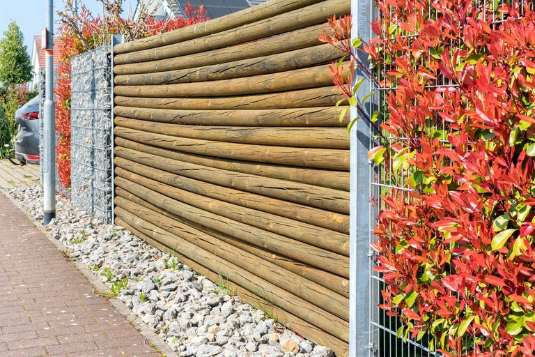 Gartenansicht mit Holzzaun, Gabionen und Bepflanzung