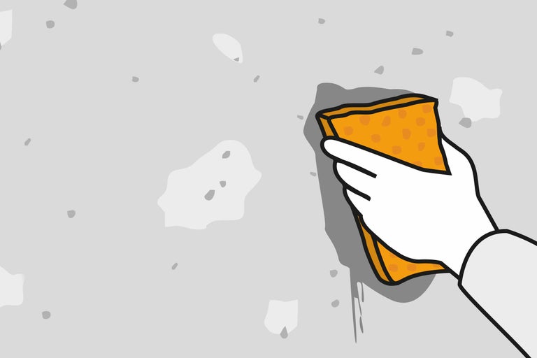 Hand mit Schwamm reinigt die Wand