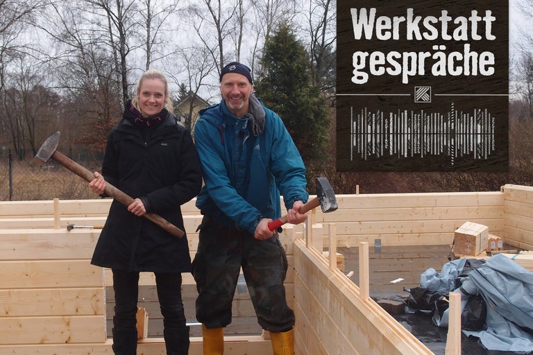 Zwei Personen mit Hämmern vor einem Holzrahmenbau mit dem Text Werkstattgespräche.