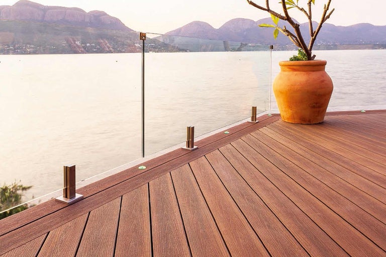 Terrasse mit Glasgeländer und Holzboden vor Seelandschaft