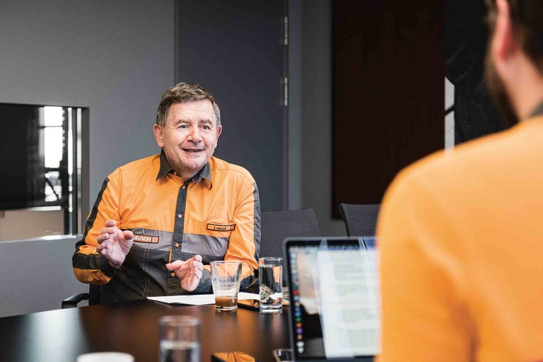 Besprechungsszene mit einer Person im orangefarbenen Hornbach-Hemd