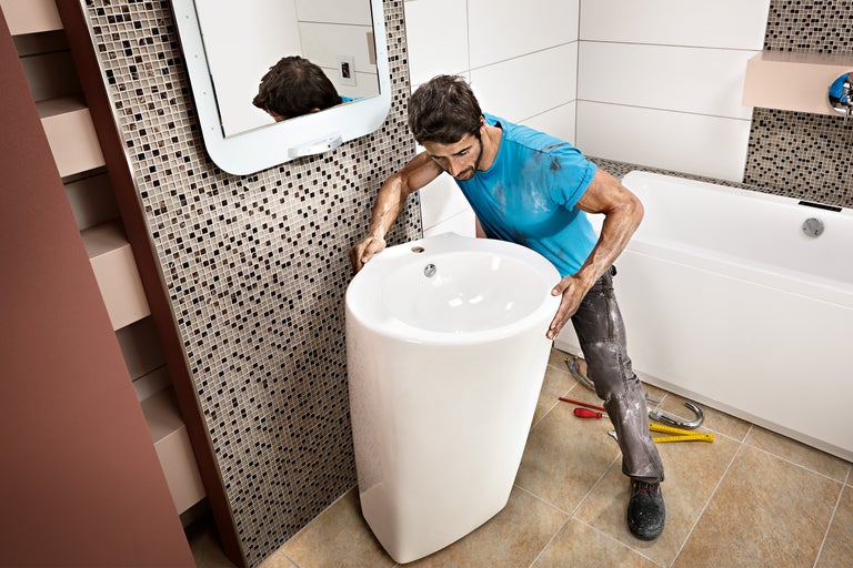 Handwerker montiert freistehendes Waschbecken im Badezimmer.