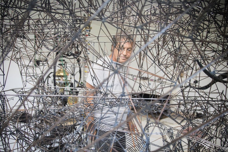 Mann steht hinter einer komplexen Metallkonstruktion