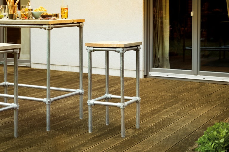Barhocker und Bartisch mit Stahlrohrgestell und Holzplatte auf einer Terrasse