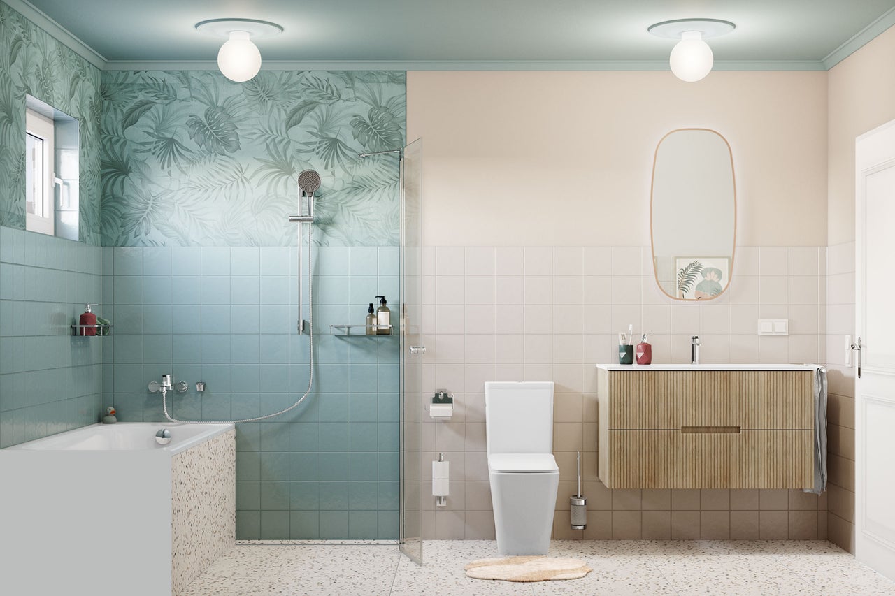Modernes, helles Badezimmer mit blauen und beigen Fliesen, Badewanne in Terrazzo-Optik, begehbarer Dusche, weißem WC und Holzwaschtisch mit Spiegel.