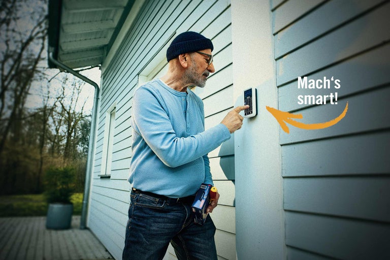 Mann bedient ein elektronisches Türschloss mit Zahlencode an einem Haus.
