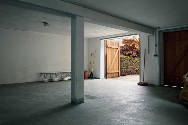 Kellerraum mit Leiter, Rechen, Besen und Holzgartentür