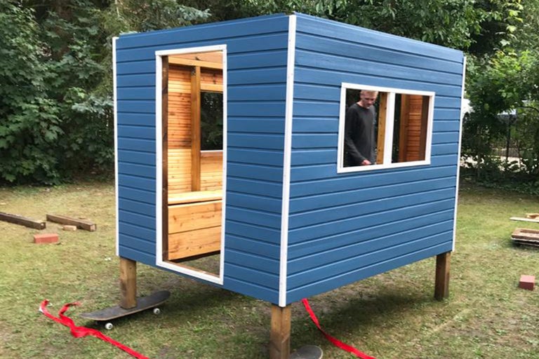 Blaues Spielhaus aus Holz mit Fenster und Tür im Garten
