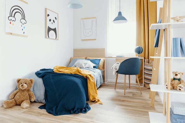 Hell und freundlich gestaltetes Kinderzimmer mit Bett, Schreibtisch und Regalen.