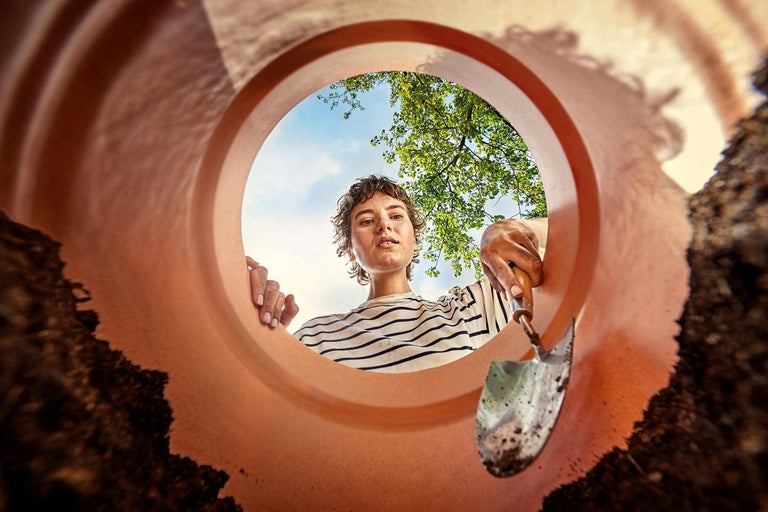 Frau mit Pflanzschaufel und Pflanzgefäß bei der Gartenarbeit