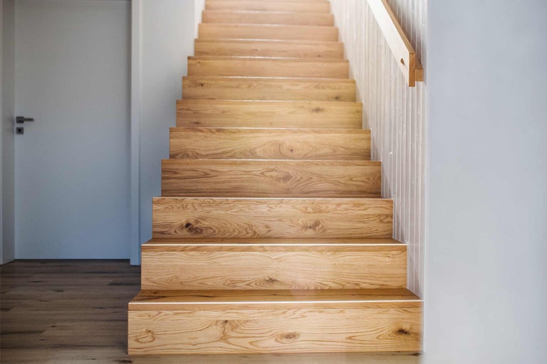 Holztreppe in einem hellen Raum mit angrenzender Tür