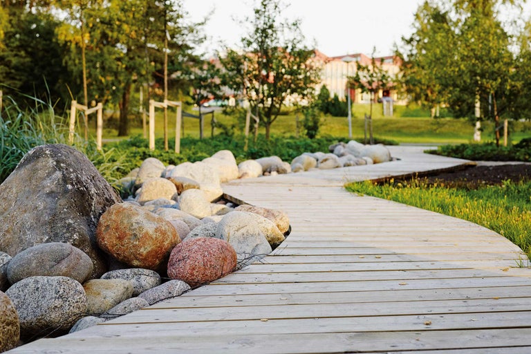 Holzsteg im Garten mit Steinen und Grünflächen