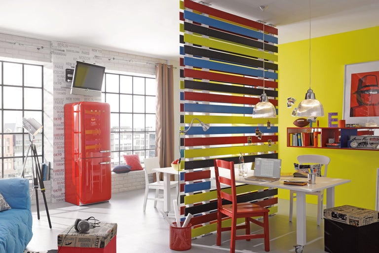 Bürogestaltung mit Raumteiler, Schreibtisch und rotem Kühlschrank