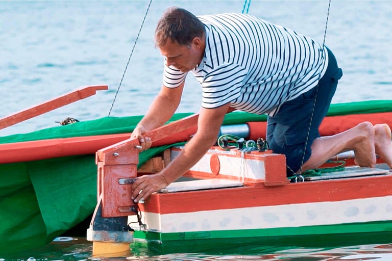 Mann, der ein Boot im Wasser repariert