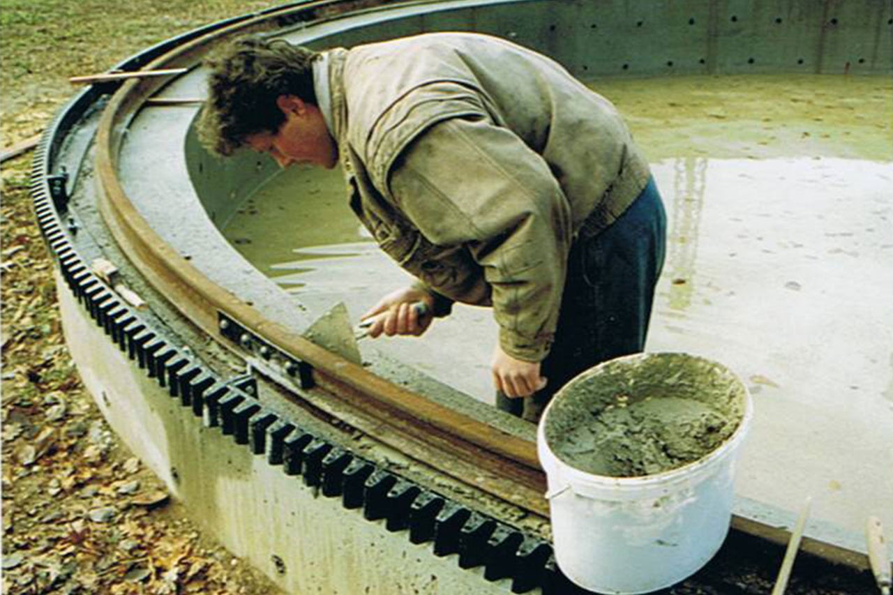 Mann arbeitet an Betonstruktur mit Zahnrad