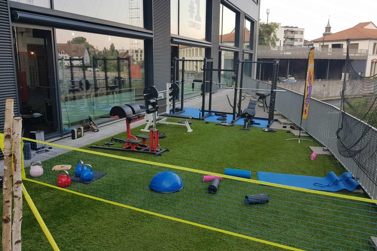 Außenbereich eines Fitnessstudios mit Fitnessgeräten und -zubehör auf Kunstrasen