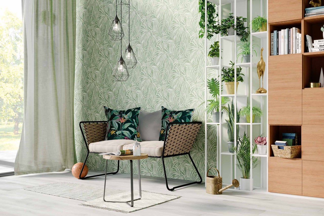 Wohnzimmer mit Sitzbank, Tisch, Stehregal, Zimmerpflanzen und Tapete mit Blättermuster