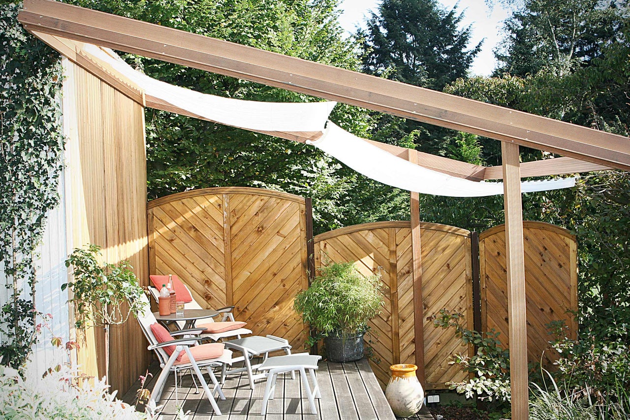 Sitzbereich im Garten mit Holzterrasse, Sichtschutzzaun und Sonnensegel