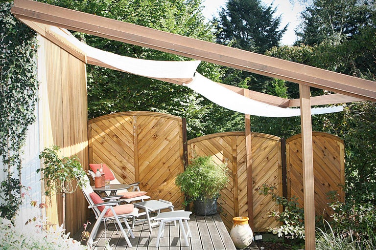 Sitzbereich im Garten mit Holzterrasse, Sichtschutzzaun und Sonnensegel