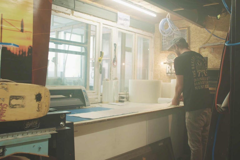 Werkstatt mit Werkbank, Werkzeug und einem Mann beim Arbeiten an einem Projekt.