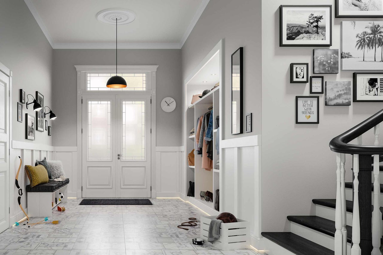 Heller Flur mit Garderobe, Sitzbank, Treppe und dekorativen Elementen wie Bildern und einer Pendelleuchte.