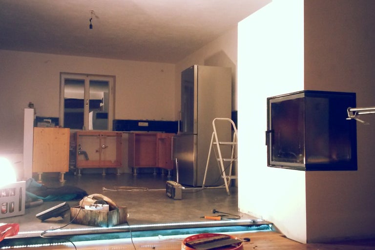 Raumbild mit noch nicht fertiggestellter Küche, Leiter, Werkzeug und eingebautem Kamin