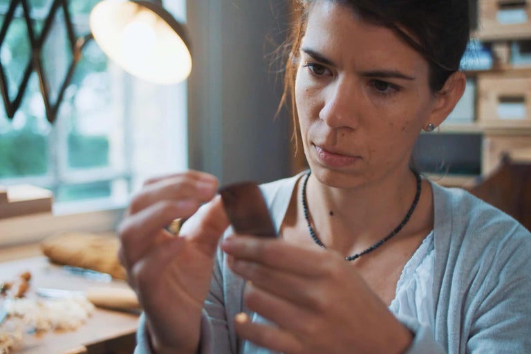 Frau prüft ein Holzstück in einer Werkstatt