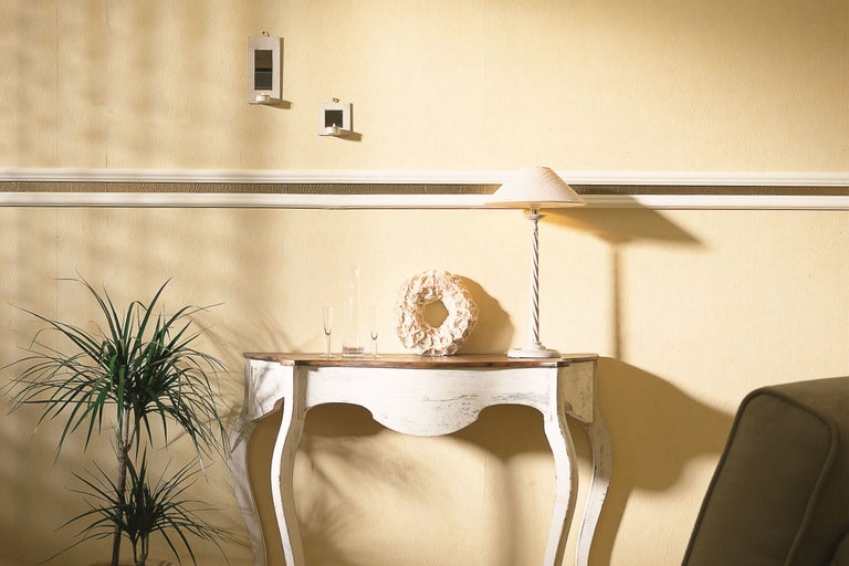 Dekoratives Interieur mit Konsole, Tischlampe und Zimmerpflanze.