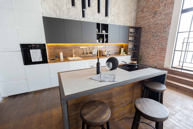 Moderne Küche mit Kücheninsel, Barhockern und Geräten.