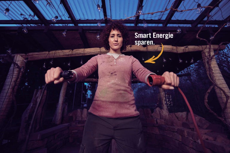 Eine Frau hält ein Verlängerungskabel unter einer Beleuchtung im Freien.