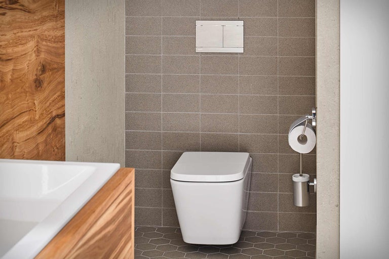Modernes Badezimmer mit wandhängendem WC, Betätigungsplatte und Toilettenpapierhalter